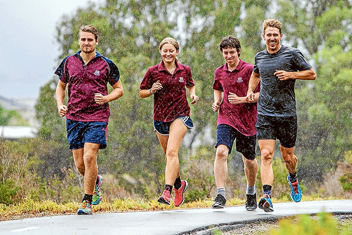 Running club: Patterson River Secondary College students Bodie McLean, left, Elise Jacob and Aidon Ward don’t let some rain stop them training with teacher Matt Clark, right, after school hours.  Picture: Gary Sissons