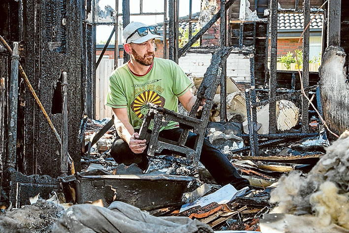 After the inferno: Mordialloc man Sam Bryant surveys the damage and what’s left of his daughter’s favourite chair after a fire destroyed his home late last month.