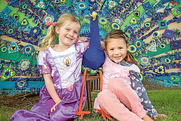 Magic peacock: Ruby, left and Luna love the colourful yarn art on display as part of this year’s storybook yarn trail. Pic: Gary Sissons