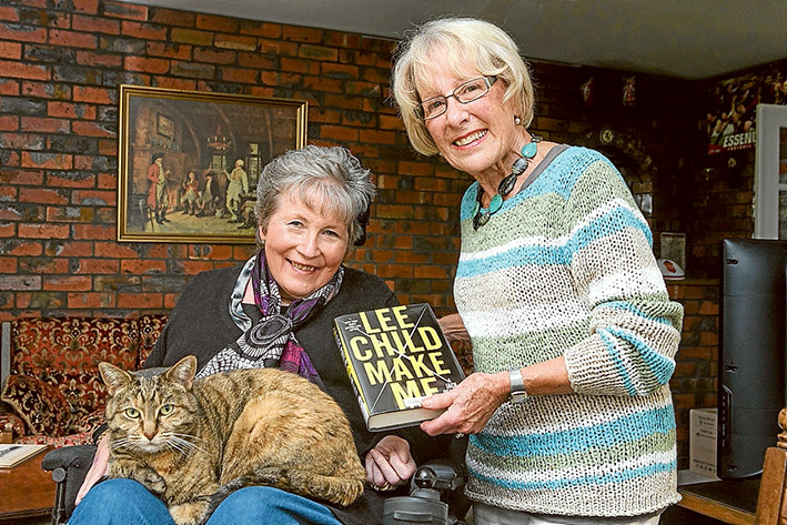Page turner: Molly the cat settles down with owner Helen Latham, left, for another thriller delivered by library volunteer Adele Parker. Picture: Gary Sissons