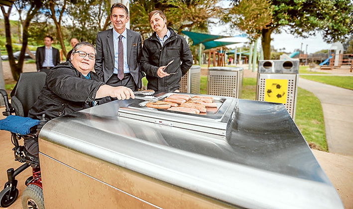 Access all areas: Frankston Council metro access events officer Anthea Haynes-Smith, left Mayor James Dooley and Christie Parkside director Alex Christie try out the new barbecue with a sausage sizzle at Frankston’s waterfront. Picture: Yanni